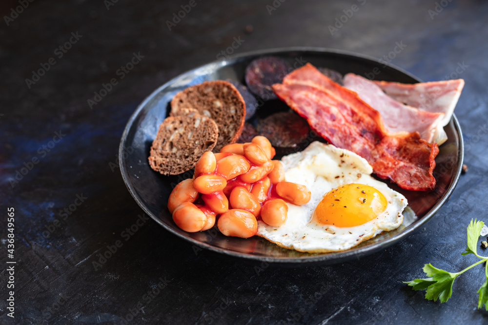 english breakfast fried egg fresh black pudding blood sausage, cereal bread, beans, bacon, scrambled eggs healthy meal snack copy space food background rustic 