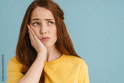Young ginger white woman with toothache looking aside photo
