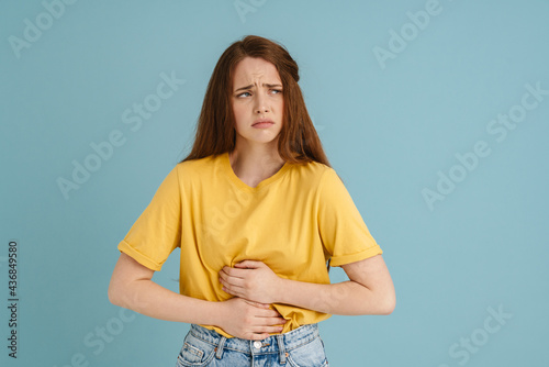 Young ginger white woman with stomachache looking aside photo
