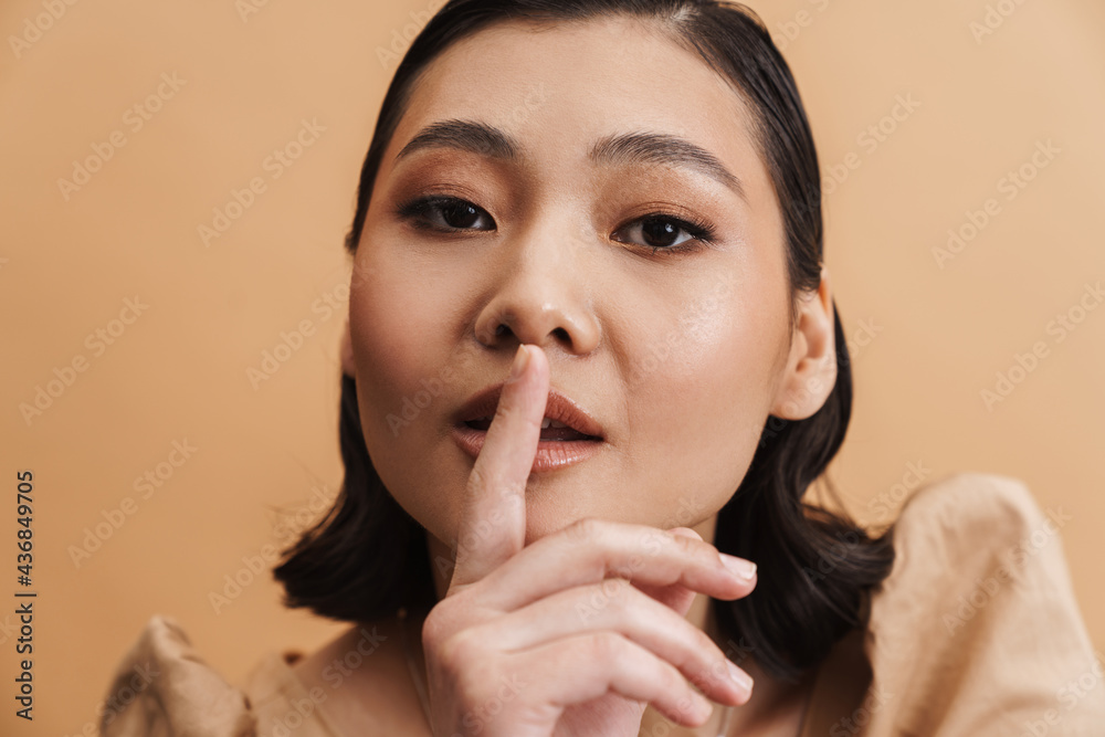 Young asian brunette woman showing silence gesture at camera Young asian brunette woman showing silence gesture at camera