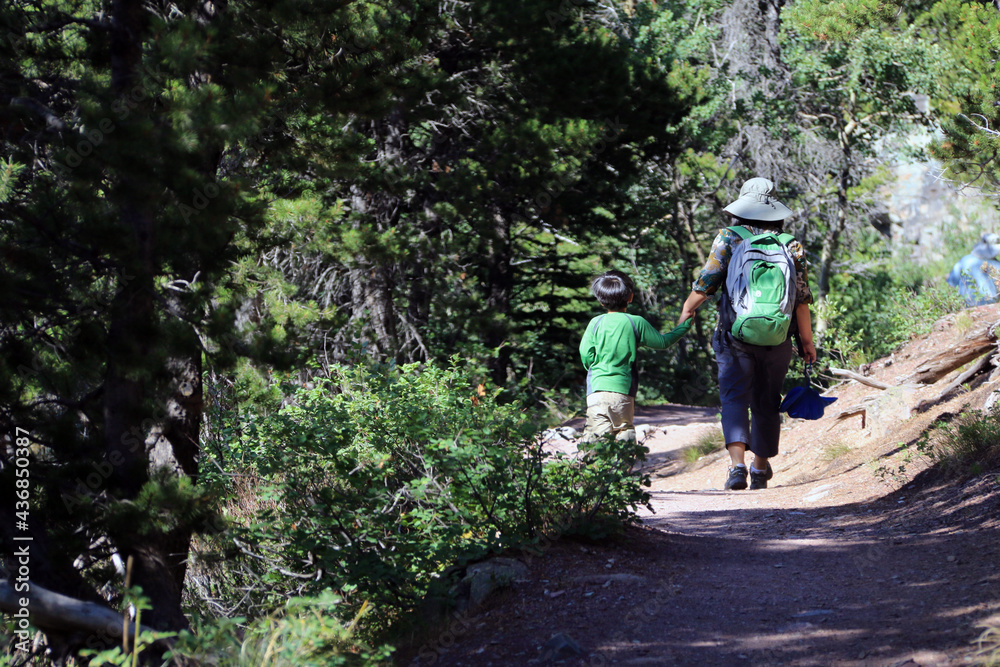 A mother and son walking on the outdoor mountain trails during summer.