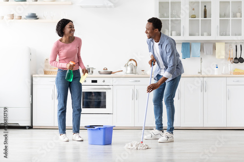 Beautiful black man and woman house-keepers cleaning kitchen photo