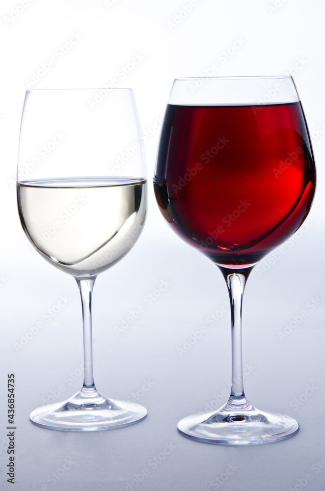 Due bicchieri di vino: un bicchiere di vino bianco e un bicchiere di vino rosso su sfondo bianco.