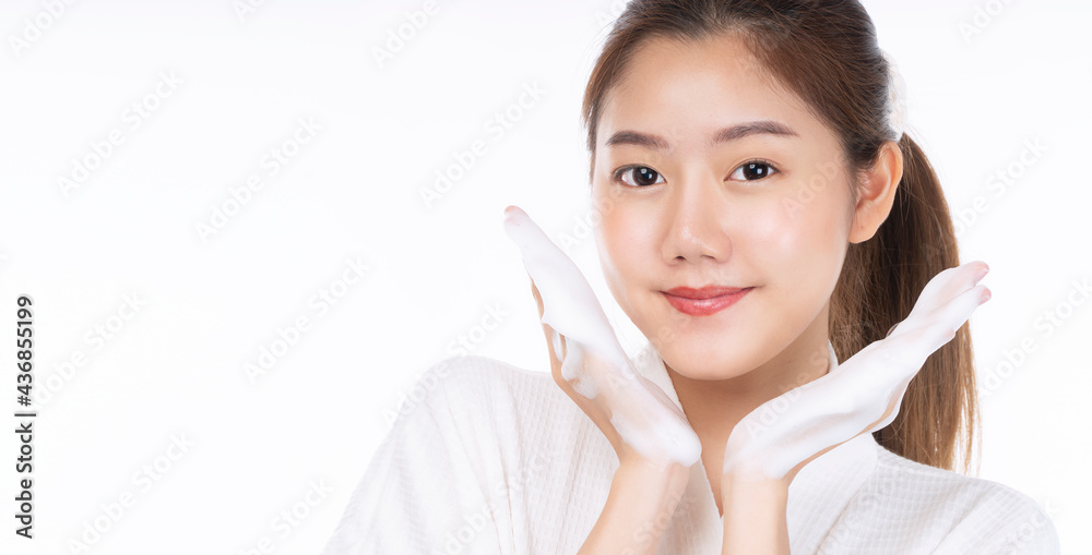 Adorable young woman washing her face with foam soap in hand while standing over isolated white background. Skin care and cosmetics concept Adorable young woman washing her face with foam soap in hand while standing over isolated white background. Skin care and cosmetics concept