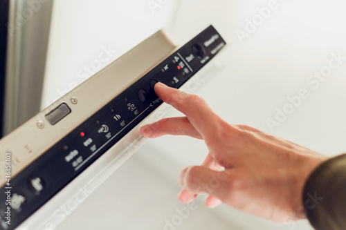 Foto Man choosing mode on the control panel of the dishwasher.