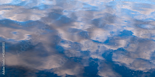 A blue sky with white clouds reflection upon the Allegheny river with water bubbles on the surface of the water in Althom, Pennsylvania, USA photo