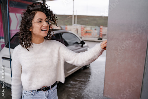 Girl use coin receptacle mounted on car wash