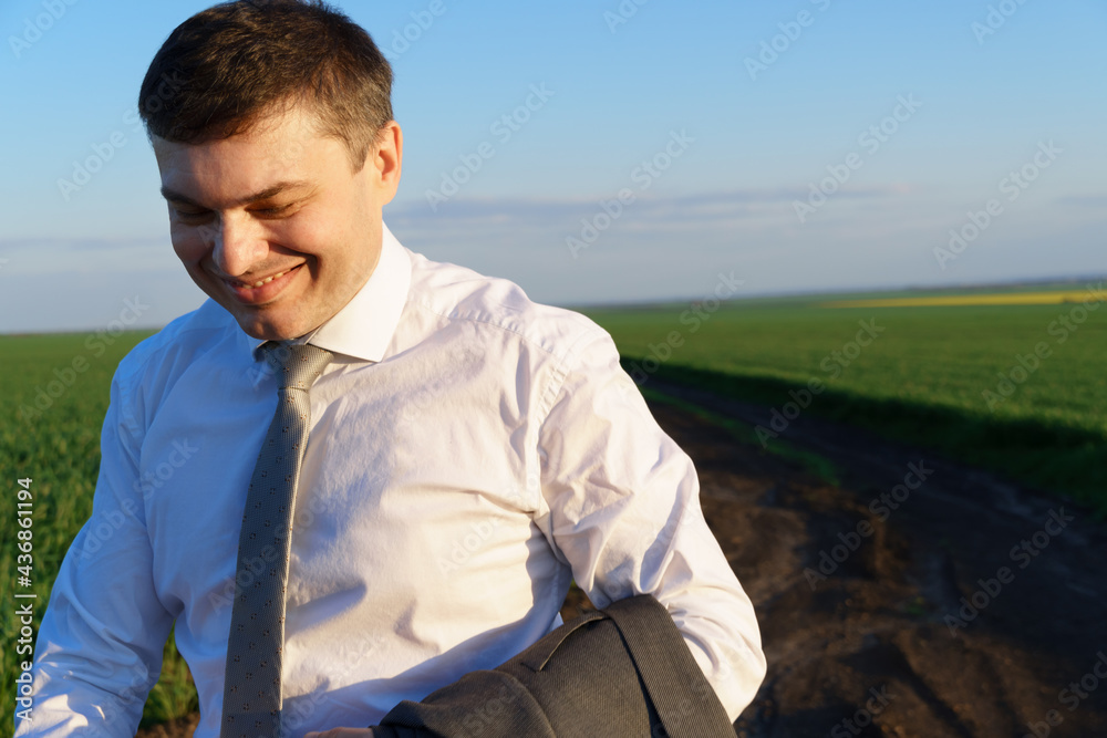 businessman walks along a country road, green field, freelance and business concept, green grass and blue sky as background