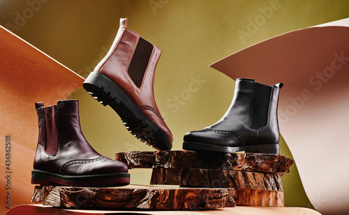 Black and brown leather chelsea boots made of genuine leather in classic style on a wooden cut. Close-up. High quality photo