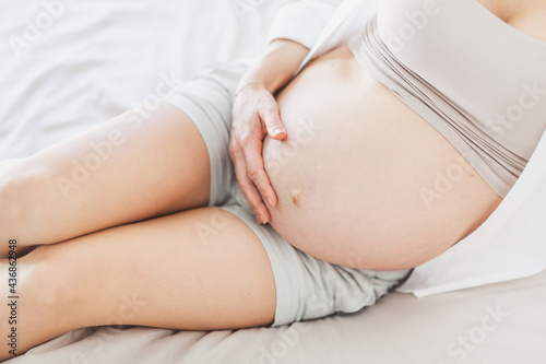 Pregnant woman sitting on bed at home