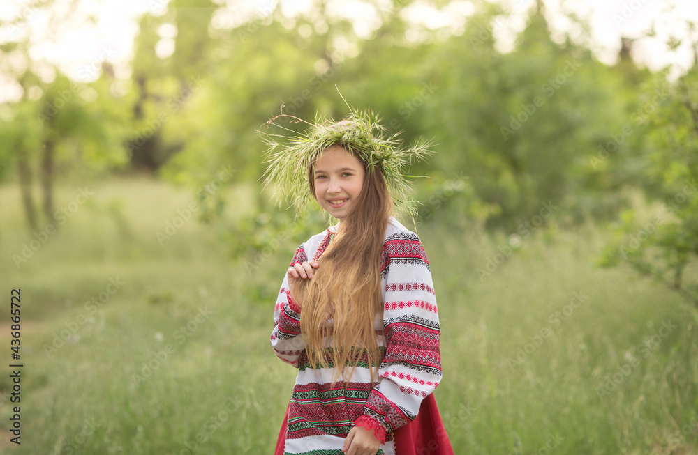 A girl in a Belarusian folk costume stands in the forest with a wreath on her head and flowers in her hands. The concept of the traditions of the Slavic people A girl in a Belarusian folk costume stands in the forest with a wreath on her head and flowers in her hands. The concept of the traditions of the Slavic people
