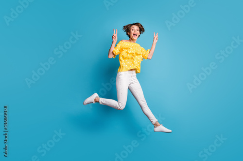 Fototapeta Naklejka Na Ścianę i Meble -  Full length profile side photo of active excited girl jump up air make v-signs isolated on blue color background