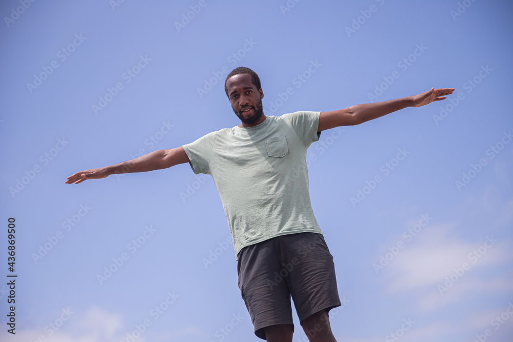 An African boy with open arms isolated with the sky as a background. Concept of youth, carefree and personal growth. An African boy with open arms isolated with the sky as a background. Concept of youth, carefree and personal growth.