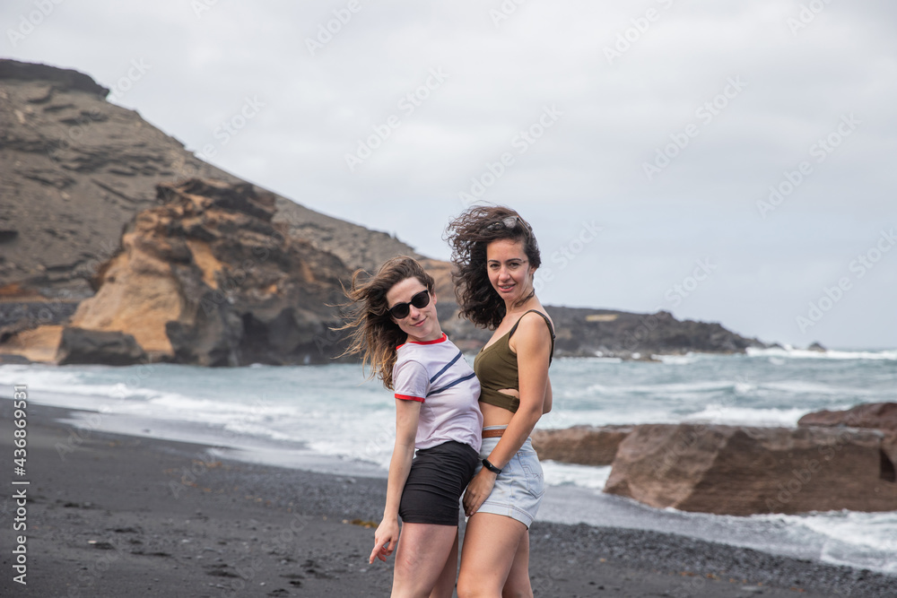 Two girls, best friends have fun at the beach and smile during their vacation