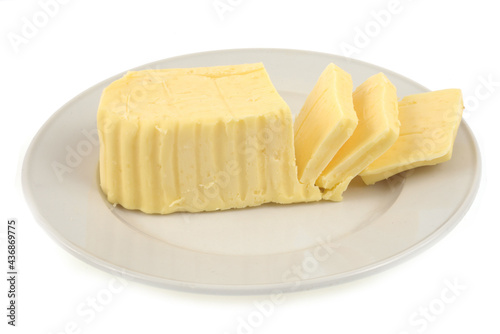 Beurre tranché dans une assiette en gros plan sur fond blanc