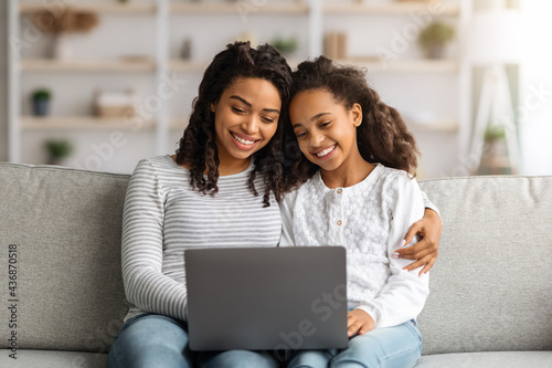 Happy african american mother and daughter using laptop together