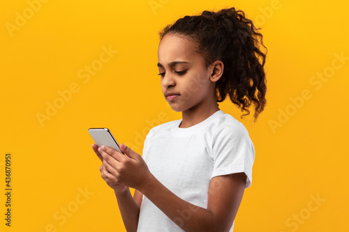 Serious black girl using mobile phone at studio