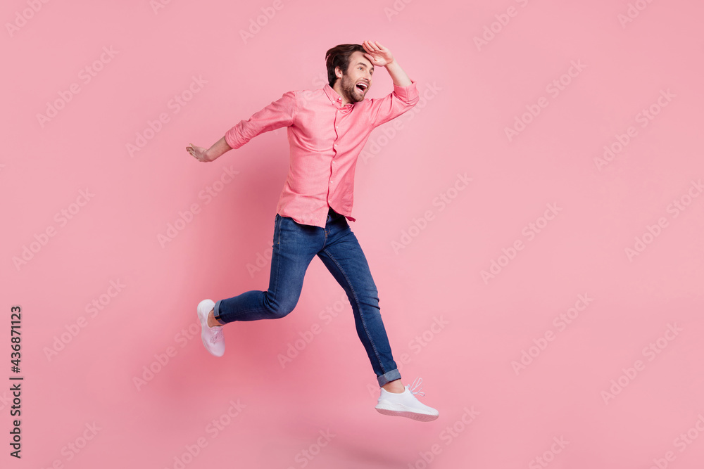Full length body size view of attractive cheerful guy jumping walking seeking news isolated over pink pastel color background