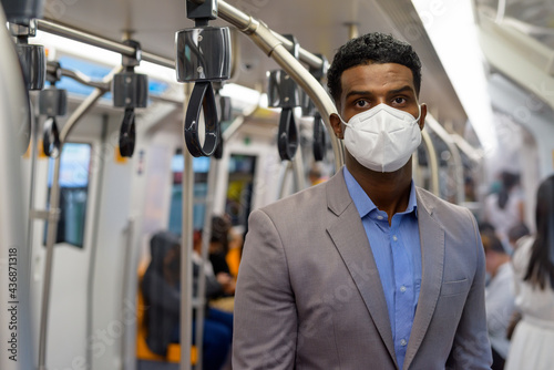 African businessman inside train wearing face mask