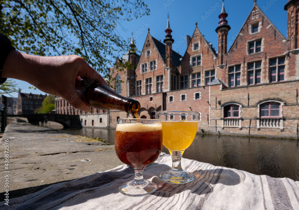 Fototapeta premium Tasting of Belgian beer on open cafe or bistro terrace with view on medieval houses and canals in Bruges, Belgium