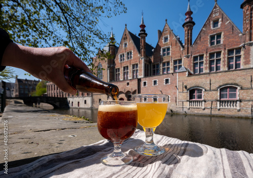 Tasting of Belgian beer on open cafe or bistro terrace with view on medieval houses and canals in Bruges, Belgium