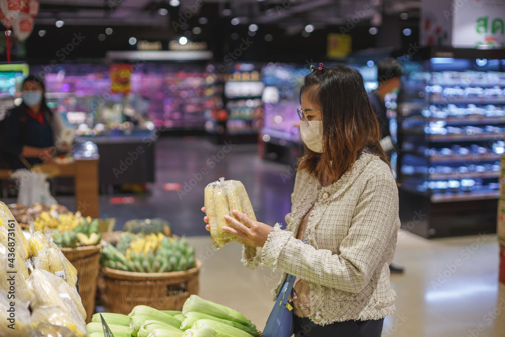 Asian woman wearing protect face mask and  shopping fruit, vegetable in grocery department store.