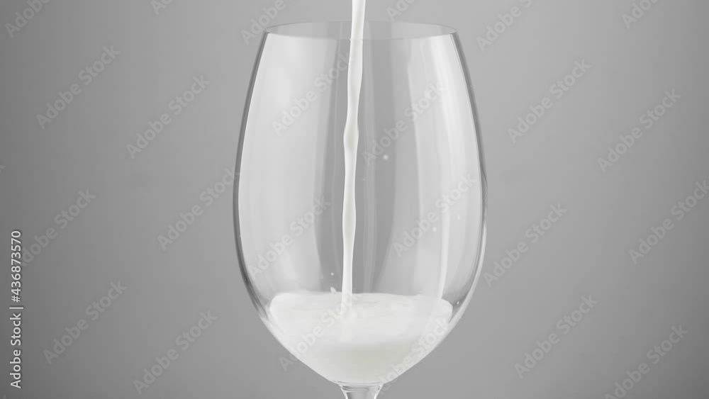 A glass into which white milk is poured on a gray background. Milk in a glass close-up.
A glass into which white milk is poured on a gray background. Milk in a glass close-up.