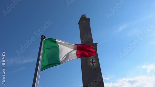 The Italian flag flying near Genoa ancient lighthouse Lanterna in Italy. Slow motion. photo