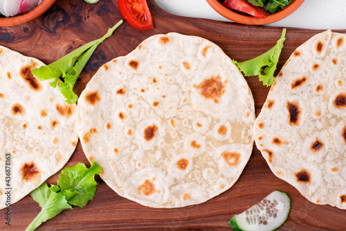 Three tortilla flatbreads and sliced vegetables on the wooden board. Cooking Mexican food, taco or fajitas photo