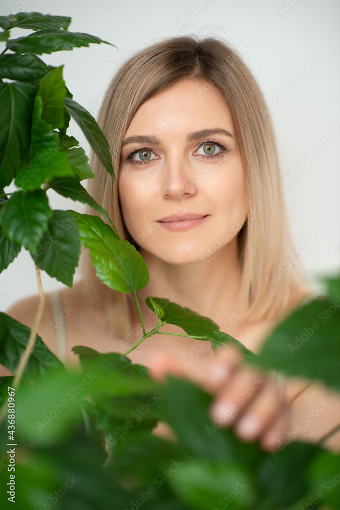 Beautiful calm middle aged woman with green plant, natural light. Anti-aging and beauty treatment. Beautiful calm middle aged woman with green plant, natural light. Anti-aging and beauty treatment.
