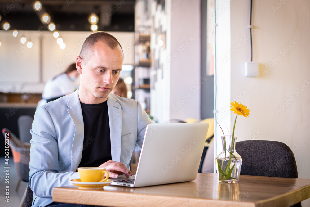 Young successful businessman sitting at coffee in a cafe and working on his laptop. Young successful businessman sitting at coffee in a cafe and working on his laptop.