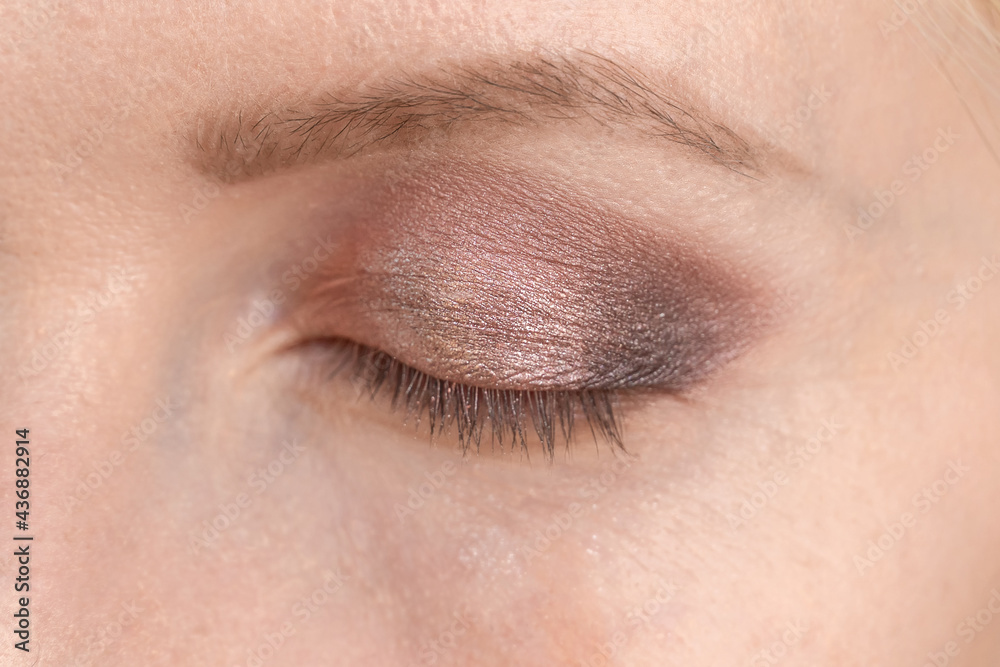 Fototapeta premium Make-up of the eyes of a young woman in brown and pink tones close-up. Next stage