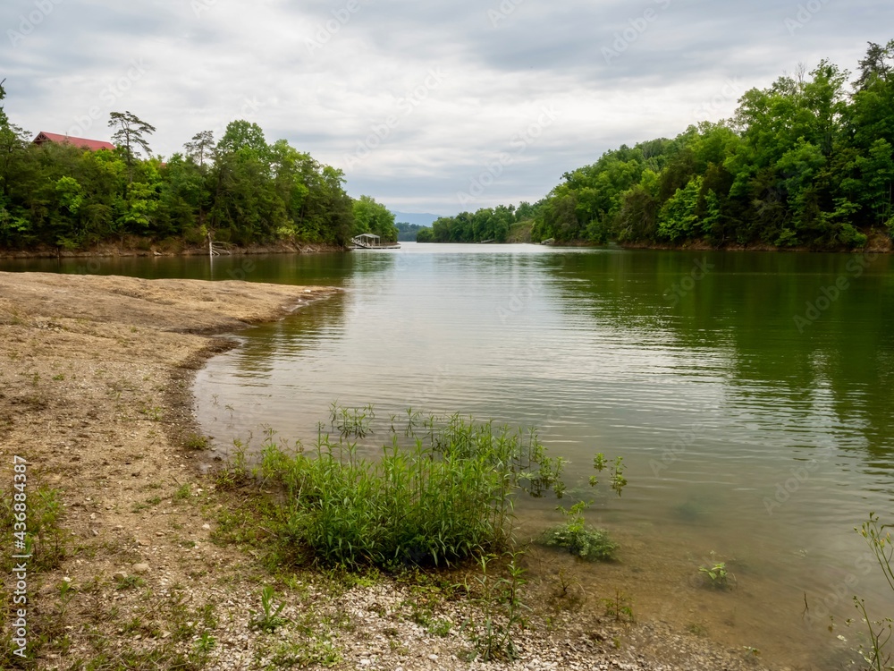 Douglas Lake in the spring in Tennessee with the Great Smoky Mountains in the background, the water and sandy shore with a blue sky filled with clouds in the distance. Douglas Lake in the spring in Tennessee with the Great Smoky Mountains in the background, the water and sandy shore with a blue sky filled with clouds in the distance.