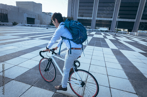 Asian businessman riding bike in city street with modern buildings in background photo