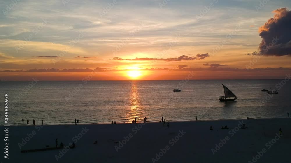 People on beach during evocative sunset over sea, Zanzibar. Aerial rising People on beach during evocative sunset over sea, Zanzibar. Aerial rising