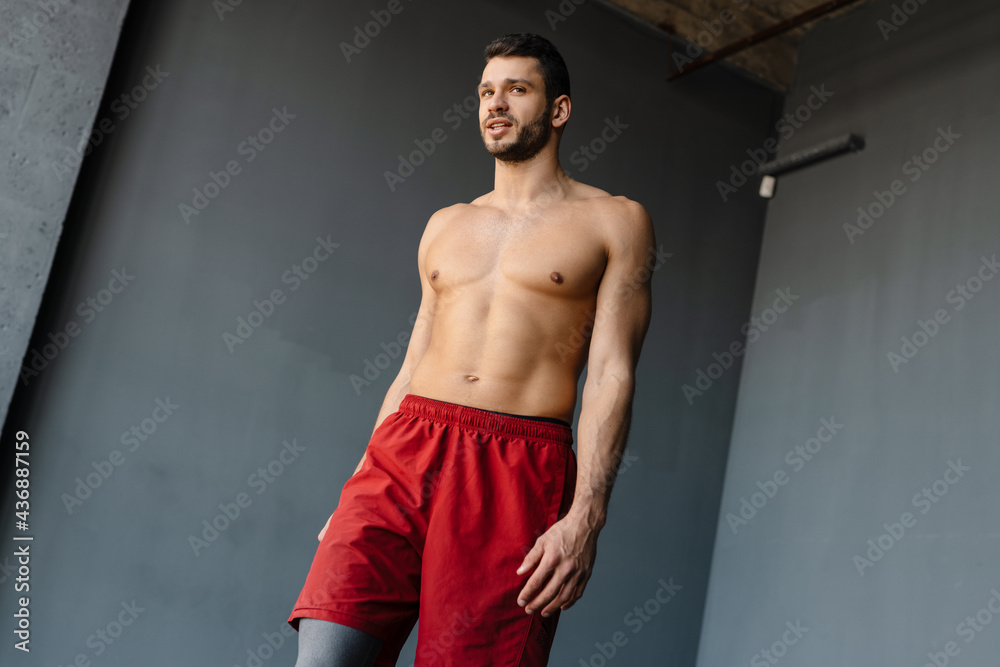 Young shirtless sportsman doing exercise while working out indoors