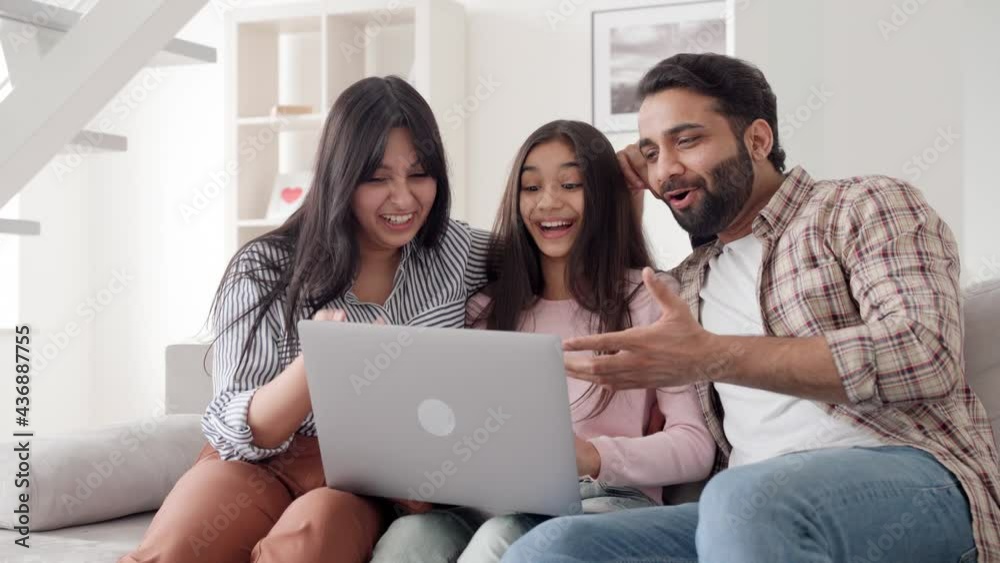 Happy family portrait. Parents with child daughter watching funny videos using laptop computer having fun enjoying spending leisure time together at home in living room sitting on sofa. Happy family portrait. Parents with child daughter watching funny videos using laptop computer having fun enjoying spending leisure time together at home in living room sitting on sofa.