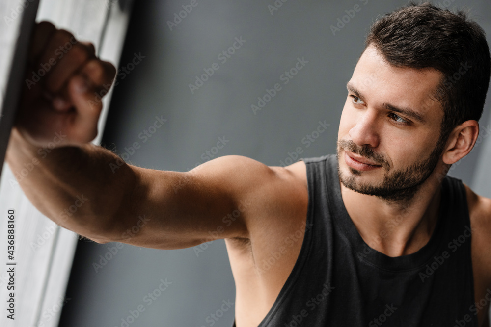 Young white puzzled sportsman looking out window indoors