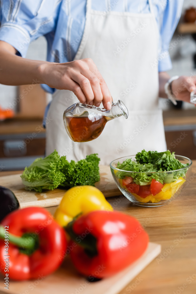 partial view of young adult woman seasoning fresh vegetables salad with olive oil in kitchen partial view of young adult woman seasoning fresh vegetables salad with olive oil in kitchen