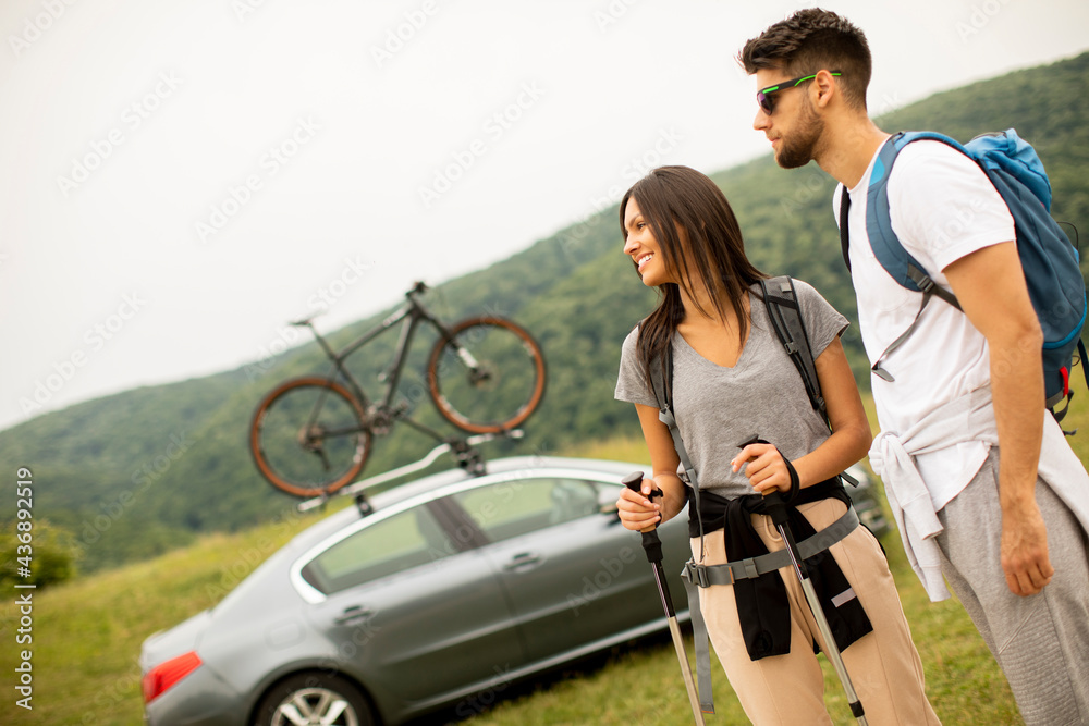 Obraz premium Smiling young couple walking with backpacks on the green hills