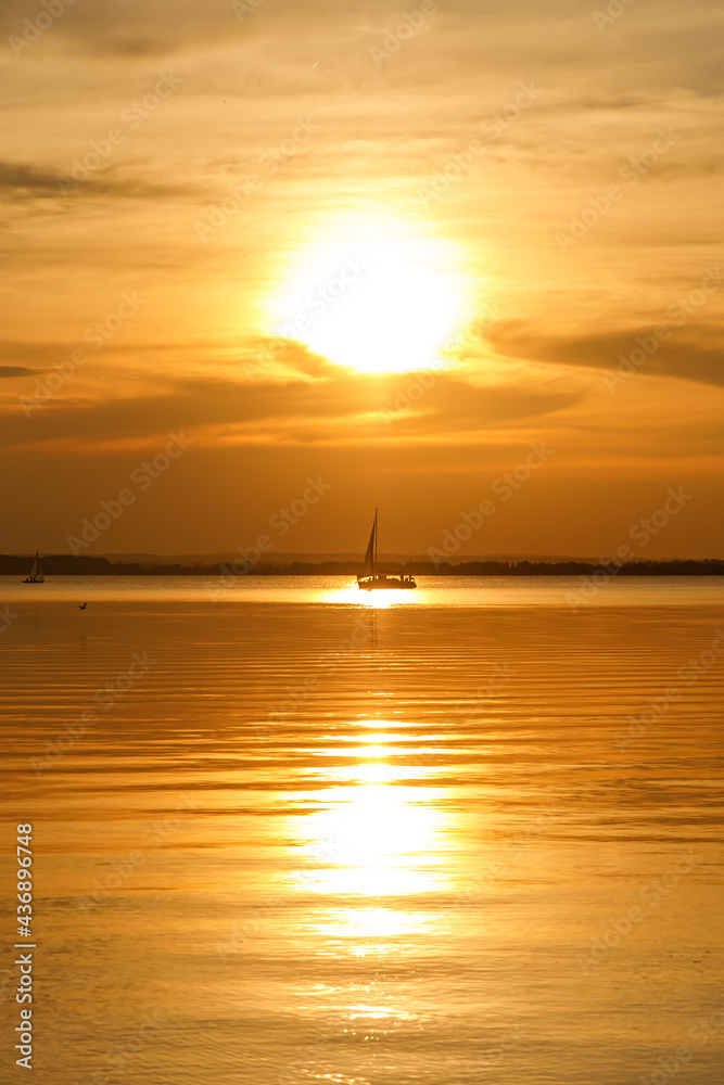 Yacht sailing against sunset. Black silhouette of sailboat.