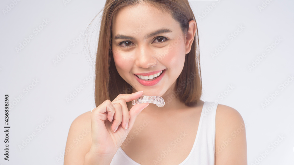 Young smiling woman holding invisalign braces over white background studio, dental healthcare and Orthodontic concept. Young smiling woman holding invisalign braces over white background studio, dental healthcare and Orthodontic concept.