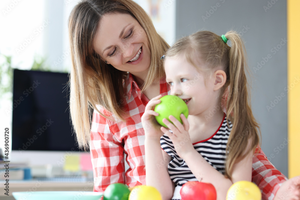 Fototapeta premium Woman has little girl on her lap and has apple