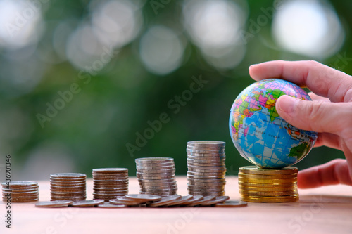 Stacking coins on table with goble on green bokeh background ,Business Finance and Money concept, business growth concept,business plan success photo