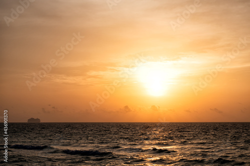 sunrise in ocean or sea water with silhouette of ship on sunset sky background, nature