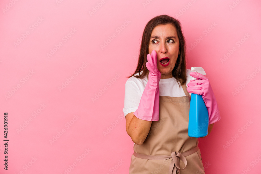 Middle age caucasian woman cleaning home isolated on pink background is saying a secret hot braking news and looking aside Middle age caucasian woman cleaning home isolated on pink background is saying a secret hot braking news and looking aside