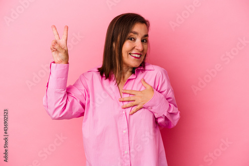 Middle age caucasian woman isolated on pink background taking an oath  putting hand on chest.