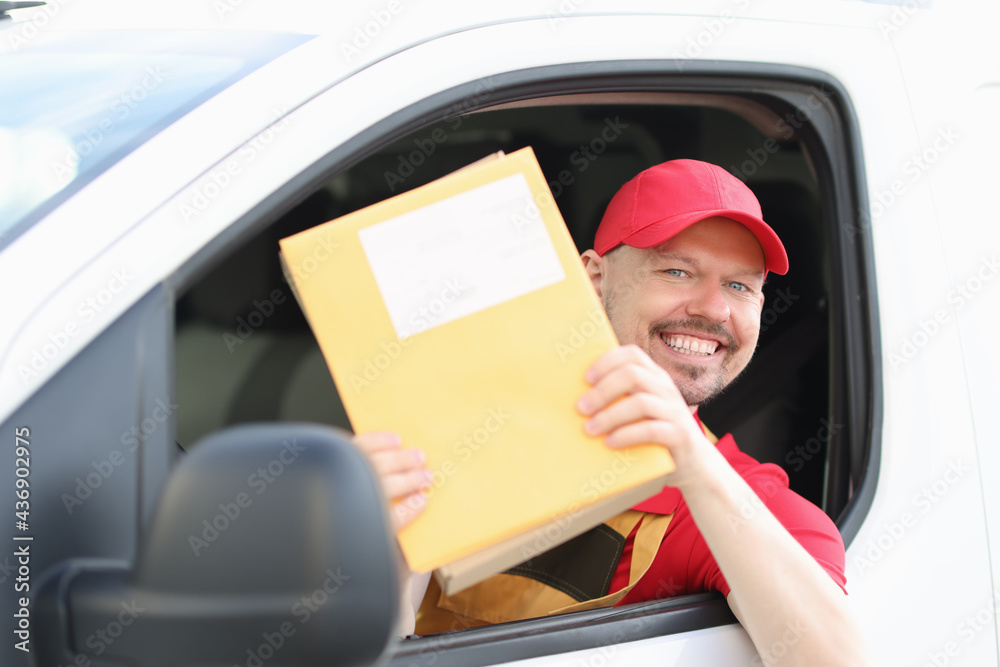 Smiling male courier driver holds mail in his hands Smiling male courier driver holds mail in his hands