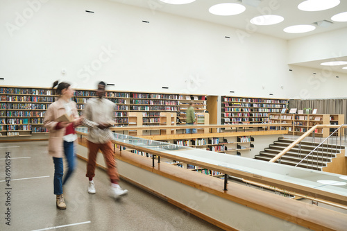 Blurred motion of people walking along the corridor in big library