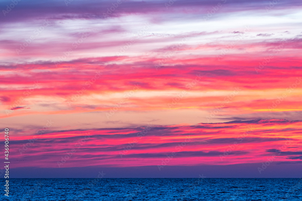 Dramatic pink purple sky at dusk over ocean at sunset